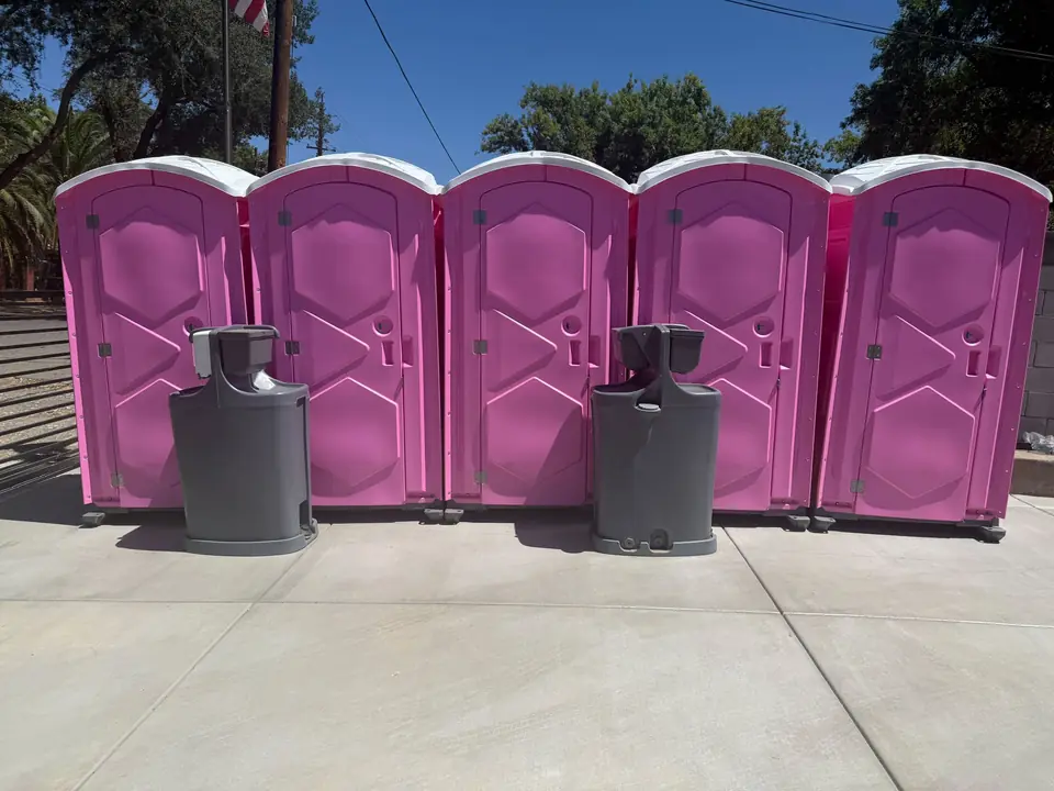 Pink event porta potties with hand wash stations set up for a party